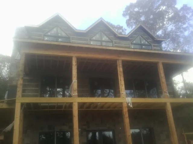 Dormers and porch framing on a large log home under construction — Roof Coating work by our crew in Mcdaniel