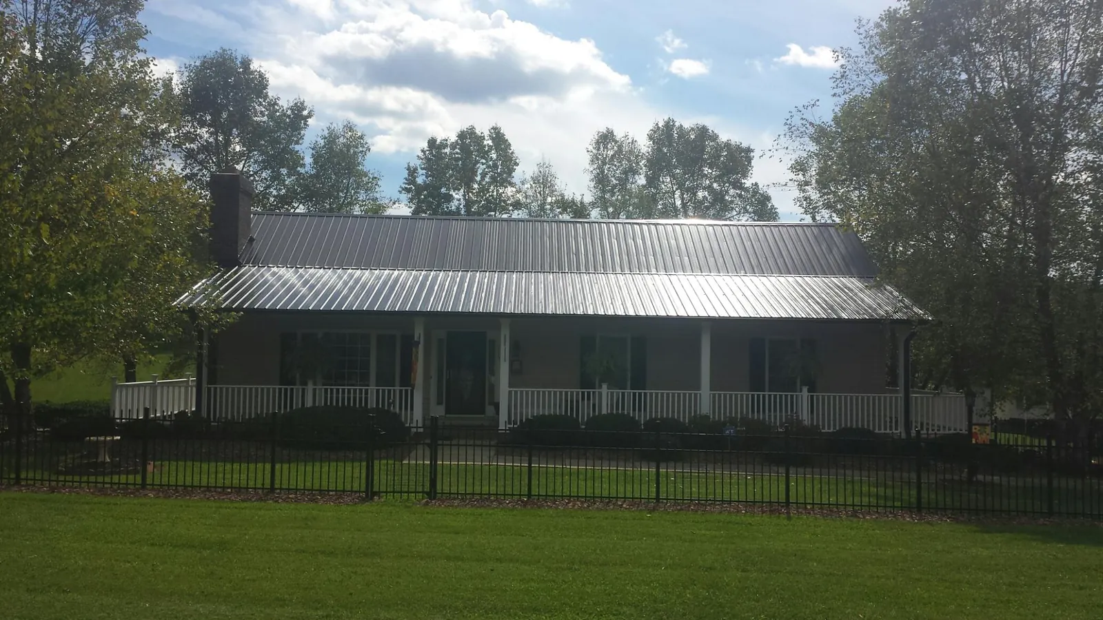 Gray metal roof on a brick ranch with a full width front porch — Gutter Guard Installation work by our crew in Mcdaniel